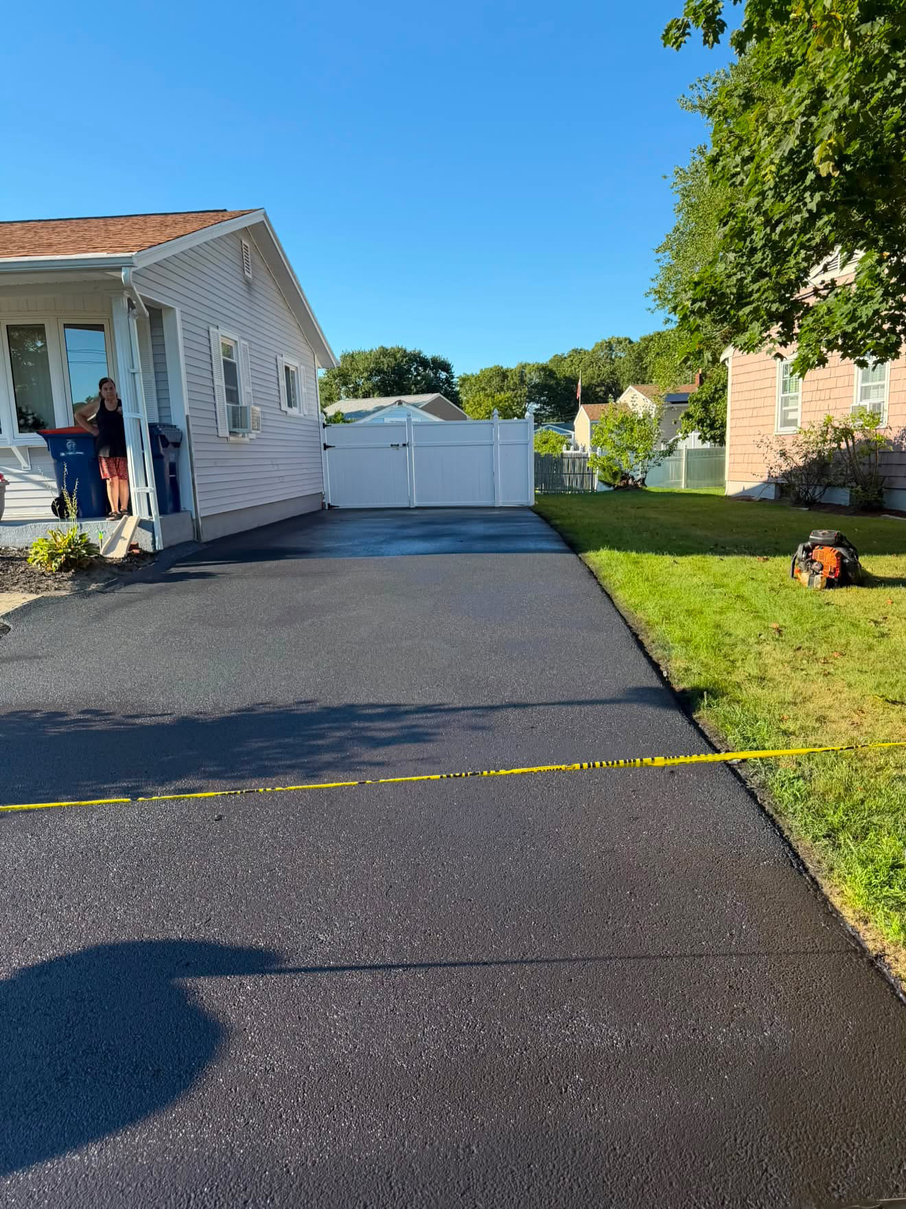 Newly sealcoated driveway taped off with caution tape while curing