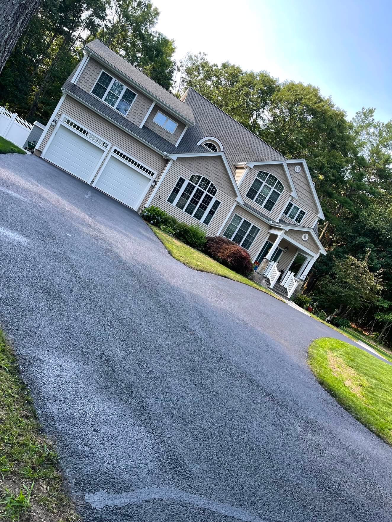 Wide sealcoated driveway in front of a navy two-story home
